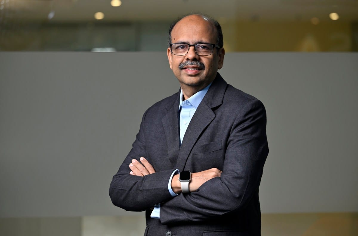 A portrait of a business professional wearing a suit, standing with arms crossed, smiling slightly.